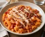 Rigatoni in cremiger Tomatensauce mit gegrilltem Hähnchen, knusprigem Bacon und Parmesan