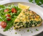 Aufgeschnittene Spinat-Feta-Frittata neben Rucola, Kirschtomaten und krauser Petersilie
