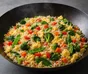 Dunkle Pfanne mit gebratenem Reis, Stückchen Ei, Spinat, Brokkoli, roter Paprika, Möhre und Zuckerschoten